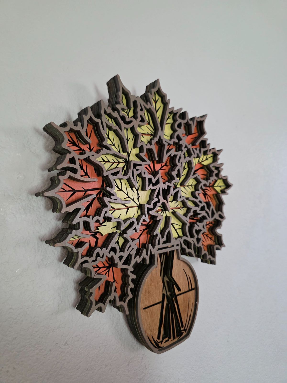 Side view of layered wooden autumn maple leaf bouquet wall art with dimensional vase and leaf layers