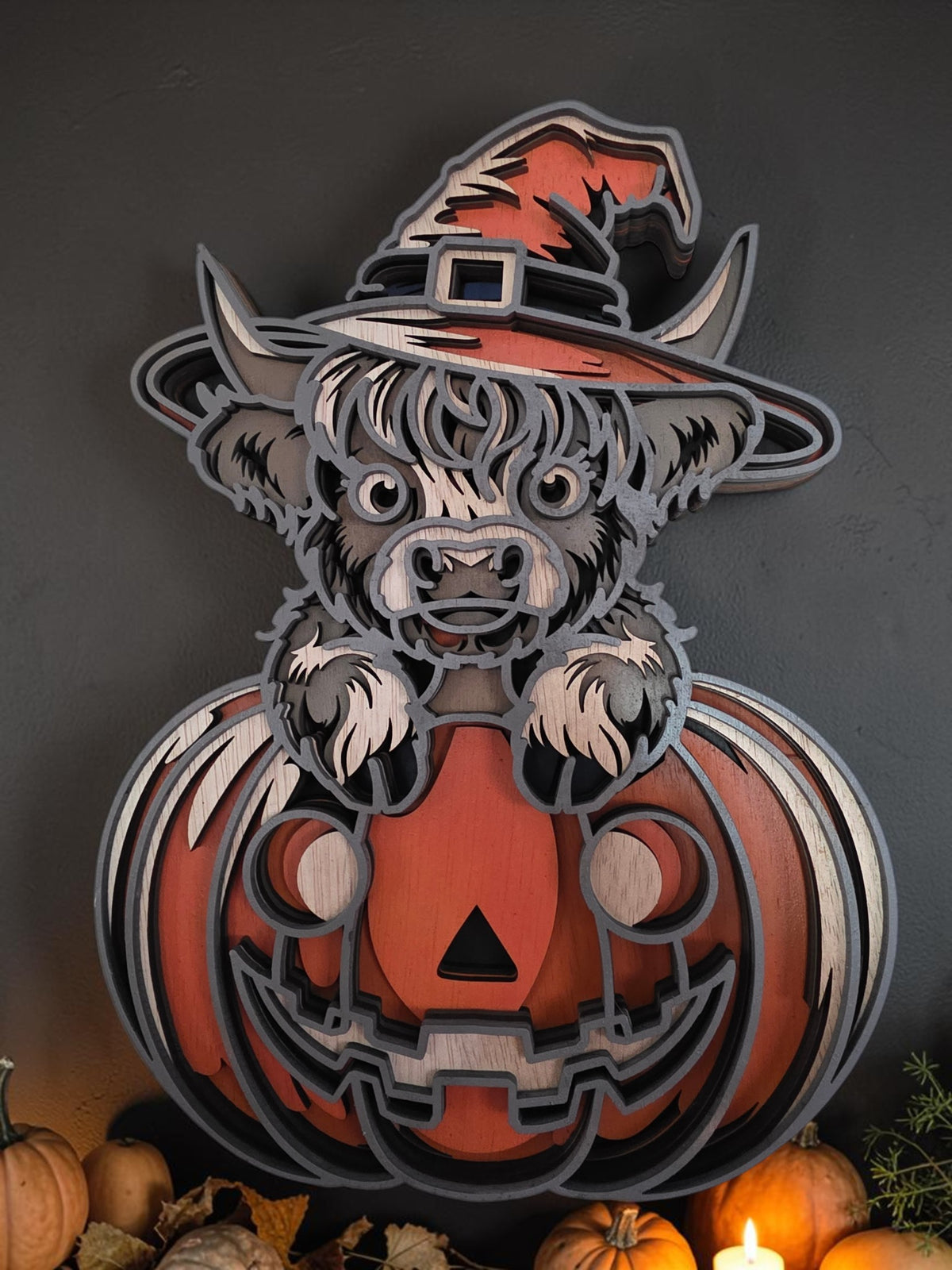 Layered wooden Highland cow wearing a witch hat sitting on a jack-o-lantern pumpkin, Halloween and fall wall decor