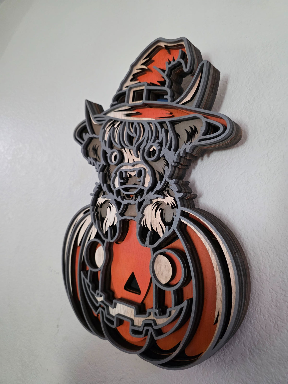 Angled side view of layered wooden Highland cow Halloween pumpkin wall art