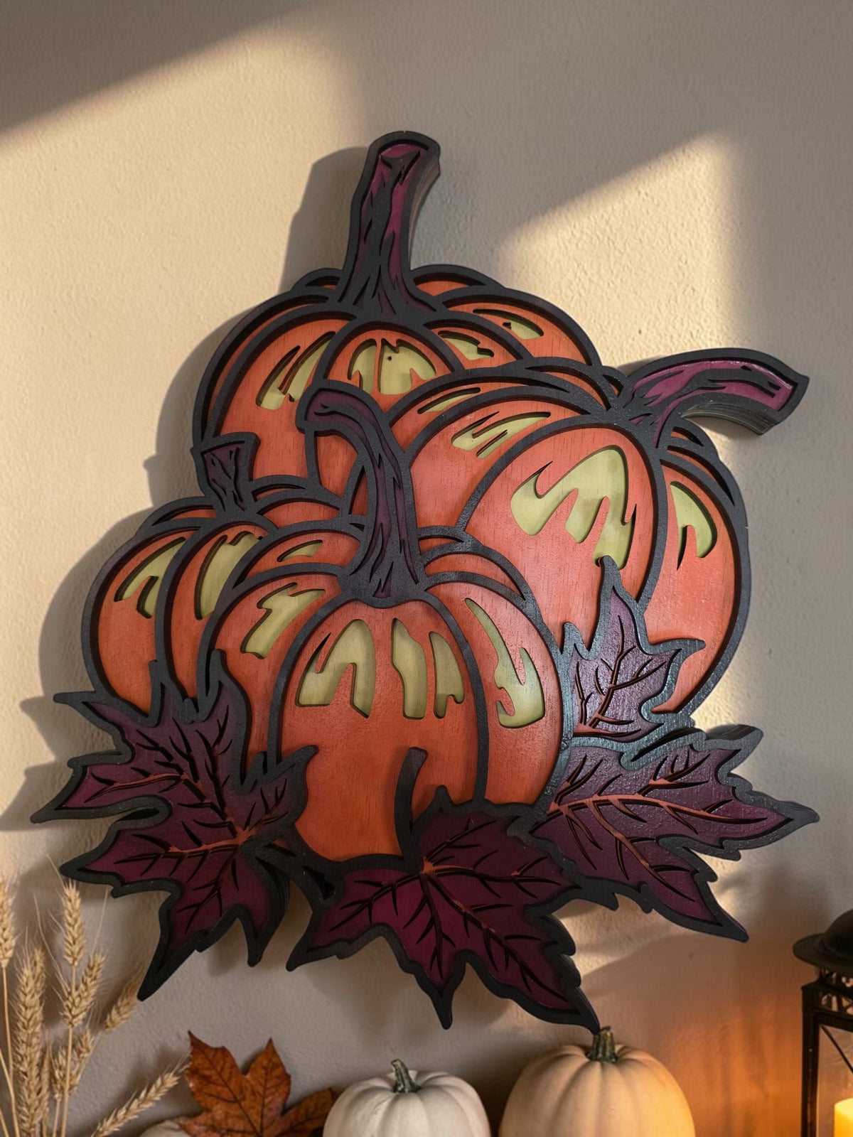 Layered wooden pumpkin and maple leaves wall art styled in warm autumn decor