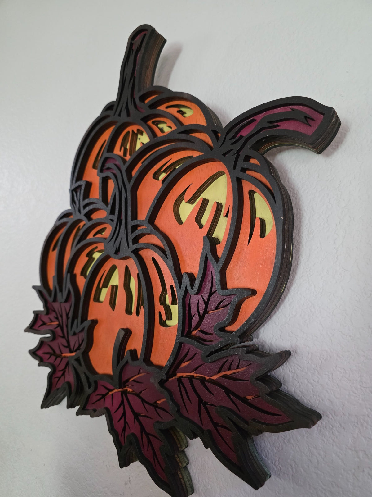 Side view of layered wooden pumpkin and autumn leaves wall art showing stacked wood construction