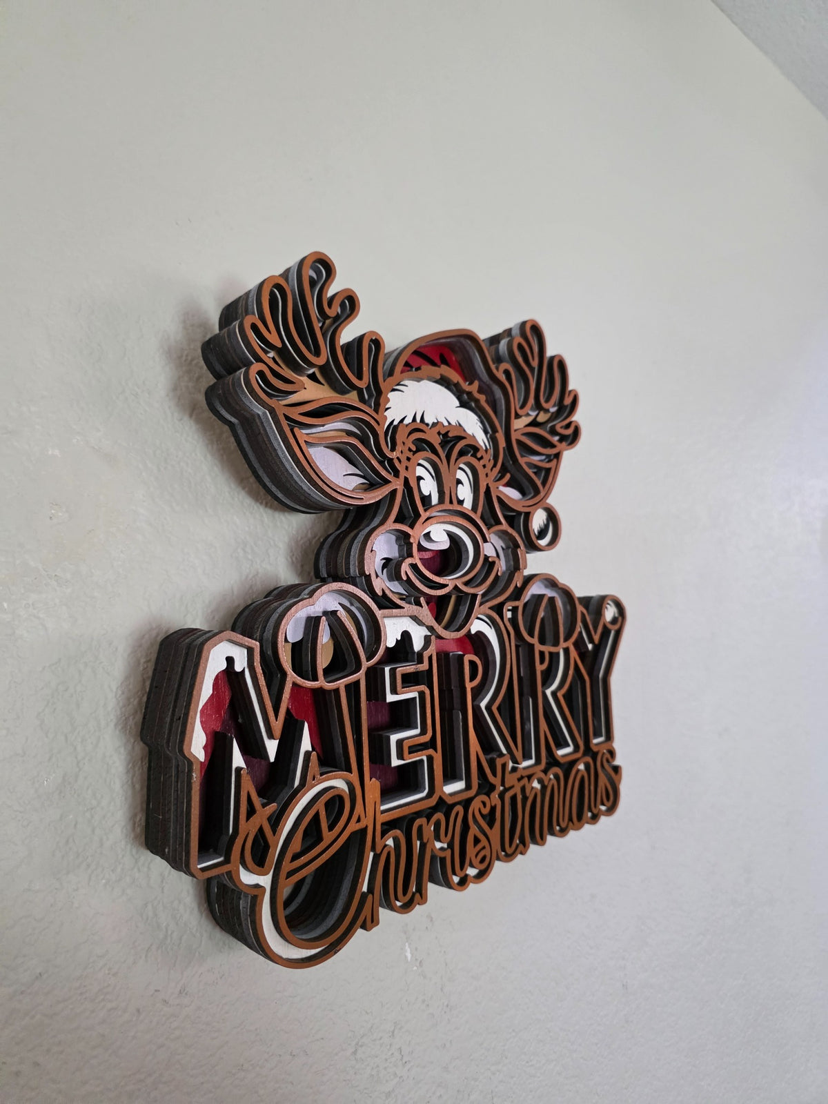 Side view of layered wooden Merry Christmas reindeer wall art showing dimensional stacked wood layers