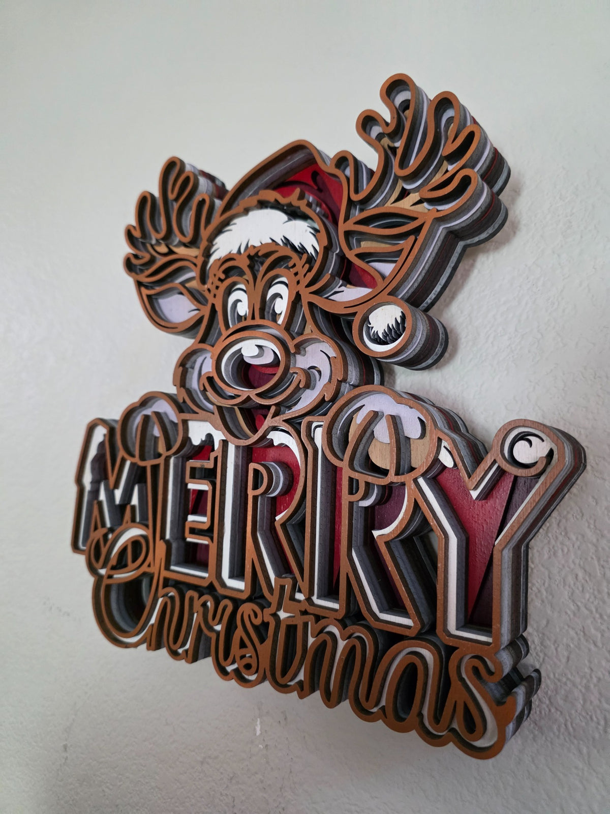 Angled view of layered wooden Merry Christmas reindeer sign showing deep layered construction