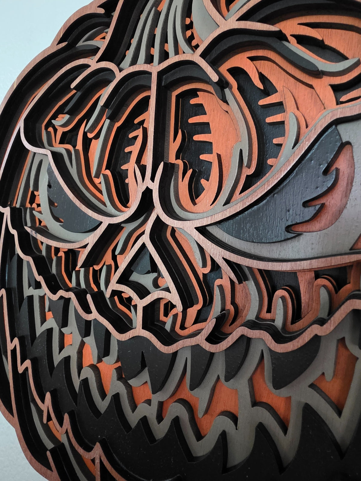 Close-up detail of sinister jack-o-lantern face on layered wooden Halloween wall art