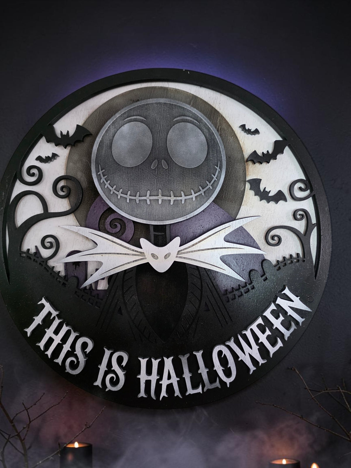 Layered wooden This Is Halloween wall art styled on a dark gothic wall with candles, fog, and purple moonlight